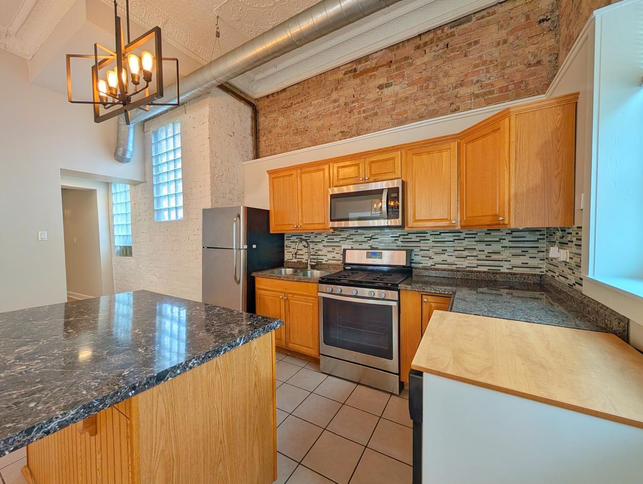 The Evergreen — kitchen in the third unit with exposed brick and tin ceiling
